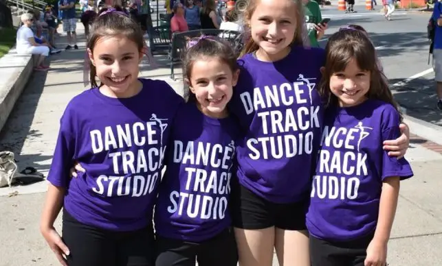 A group of young girls wearing purple shirts.