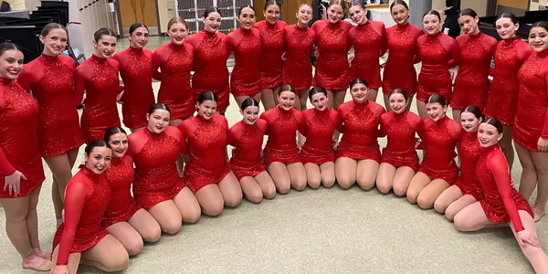 A group of girls in red outfits sitting on the floor.